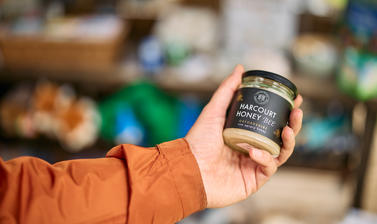 A person holds up a jar of Harcourt Honey at the Arboretum shop