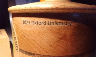 A close-up of the BUC 2023 trophy. It is hand-turned wood. '2023 Oxford University' is engraved on the side.