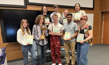 The Oxford and Cambridge team stand, smiling with their prizes